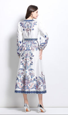 Woman in a Long-Sleeve Paisley-Print Casual Maxi Wrap Dress featuring blue and red patterns, paired with silver high heels, facing away from the camera against a plain white background.