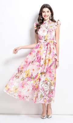 Woman models the High-Neck Long Print Casual Dress with Cap Sleeves in Pink Multi, featuring an ankle-length floral design, against a white background. She pairs it with light-colored heels.