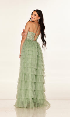 A woman stands smiling over her shoulder in the Cecilia Couture 2613 long prom dress, featuring light green tiered tulle, an embroidered corset bodice, and a lace-up back against a plain background.