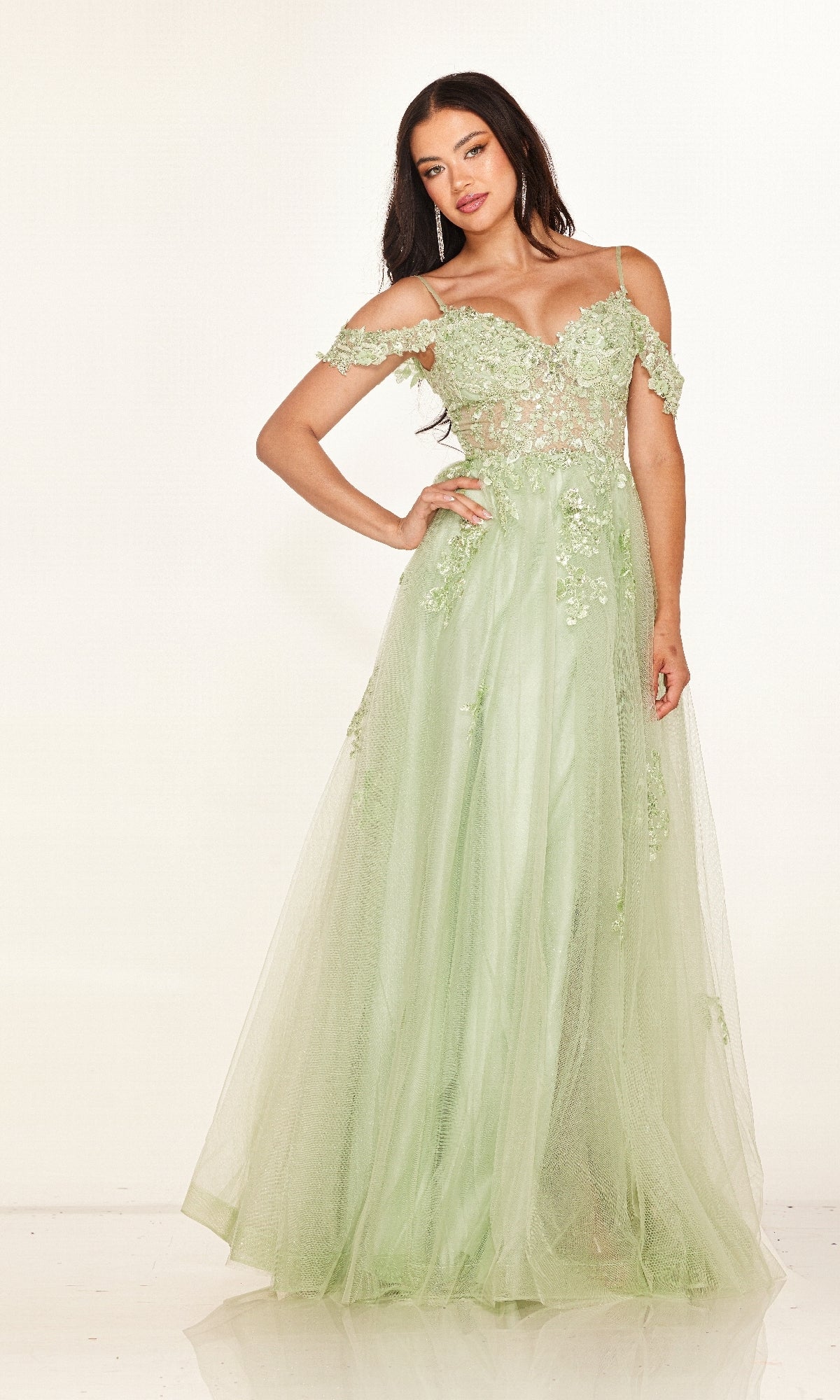 A woman models the Cecilia Couture 2618, a light green, off-the-shoulder long prom dress with floral lace detailing, posing gracefully against a plain white background.