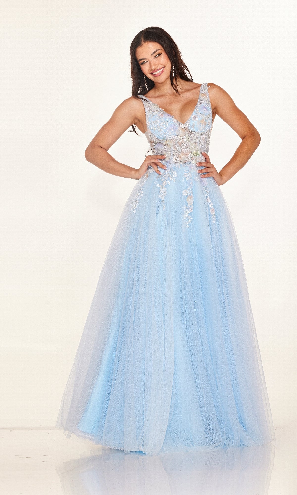 A woman stands smiling in the Cecilia Couture 2619 long prom dress, a light blue sleeveless gown with floral embroidery, a floor-length tulle skirt, and delicate embellishments.