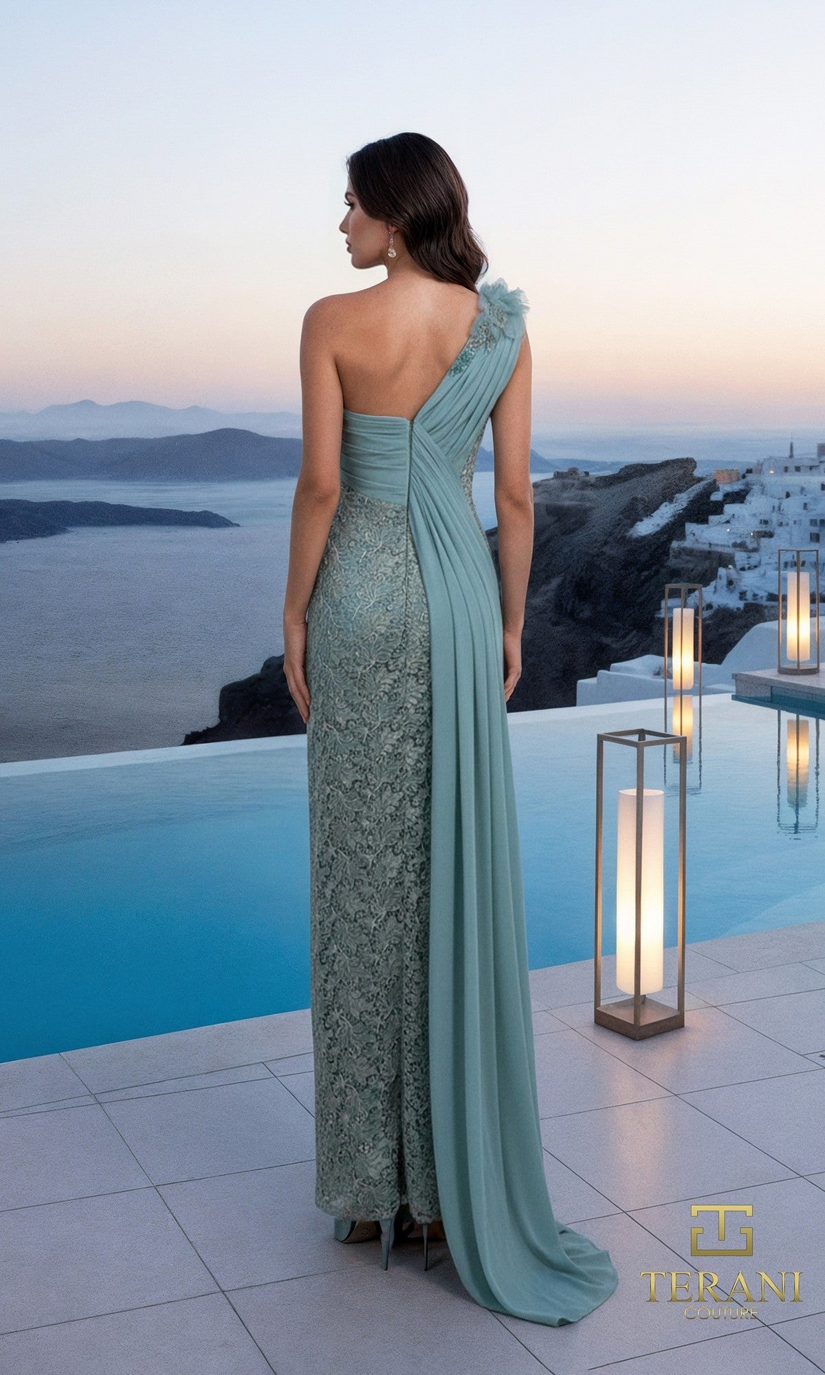 A woman in a Terani 261E6257 long formal dress stands by a pool, overlooking the sea and white buildings at sunset.