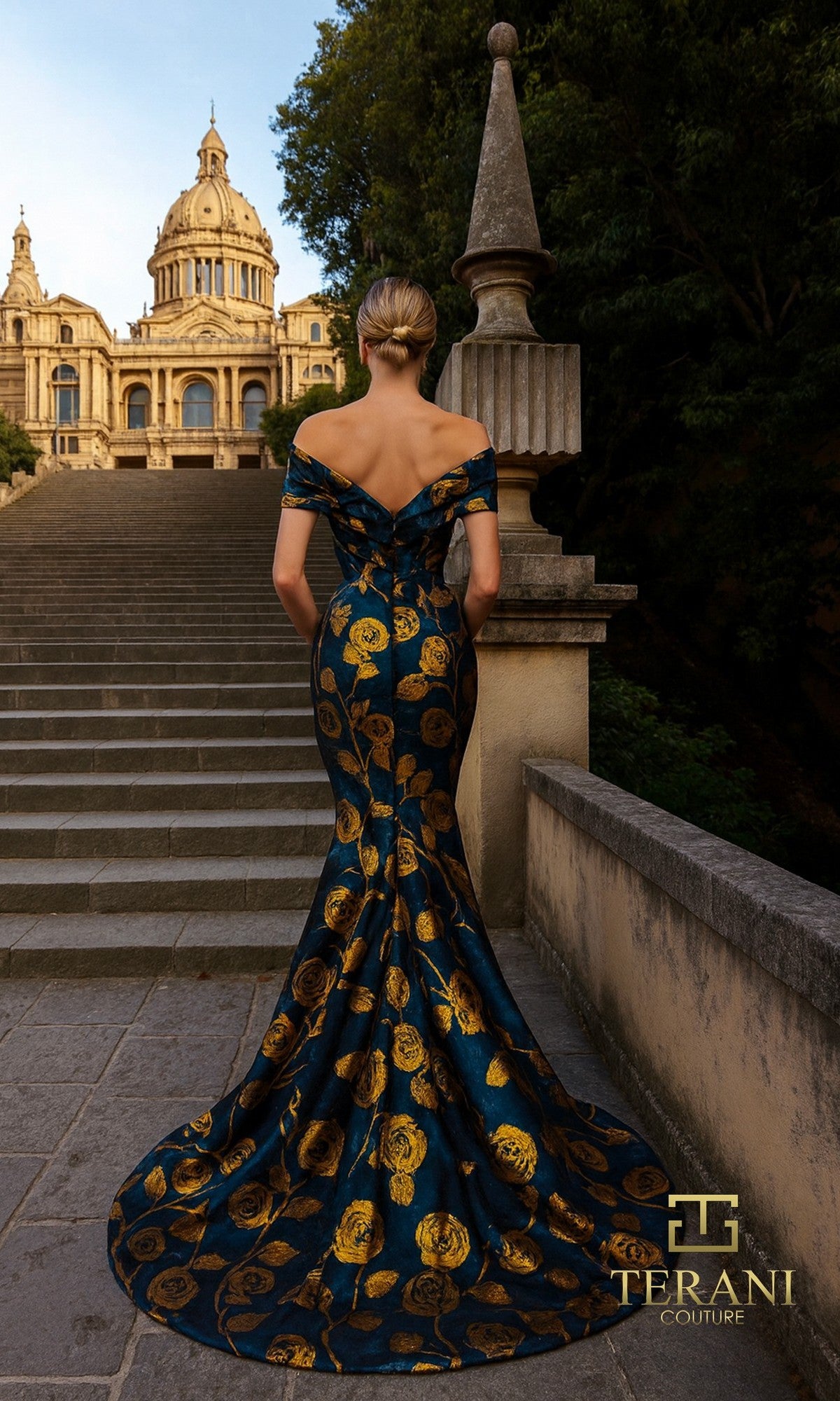 A woman in the Terani 261E6273 Long Formal Dress stands on outdoor stone steps, facing away from the camera, with a grand building in the background.