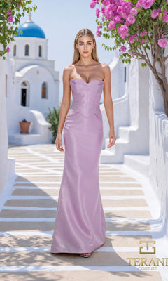 A woman in the Terani 261E6292 long formal dress in orchid stands on a sunlit walkway, surrounded by white buildings, a blue dome, and pink flowers. The Terani Couture logo is visible.