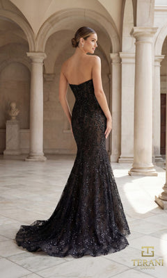 A woman in the Long Formal Dress: Terani 261GL6001, featuring a strapless beaded bodice and mermaid silhouette, stands in an elegant hall with marble columns, facing away from the camera.