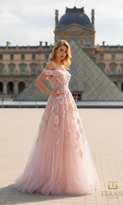 A woman in a blush Terani 261M6435 long formal dress poses outdoors in front of the Louvre Pyramid in Paris.