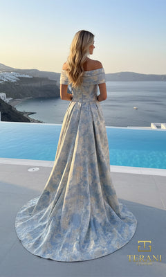 A woman in the Terani 261M6444 long formal dress stands by a pool overlooking the sea and cliffs, her off-the-shoulder, floor-length jacquard gown elegantly patterned in blue shades.