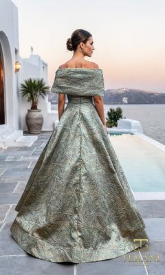 A woman in a Long Formal Dress: Terani 261M6453 stands by a pool, facing away, with white buildings and water in the background.