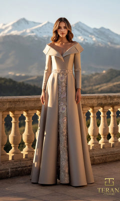 A woman in the taupe Terani 261M6455 long formal dress with lace and Mikado fabric stands on a stone terrace, mountains and clear sky behind her.