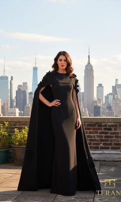 A woman stands on a rooftop in the Terani 261M6687 long formal dress, with its elegant column silhouette and cape, the Empire State Building and city skyline rising behind her?an unforgettable vision of Terani Couture style.