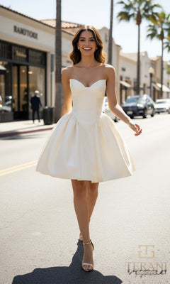 A woman in the Terani 261P6176 short prom dress and sandals walks down a sunny street lined with palm trees and shops.