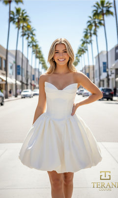 A woman in an ivory fit-and-flare strapless Terani 261P6176 dress stands smiling in the middle of a palm-lined city street. The Terani Couture logo appears in the lower right corner.
