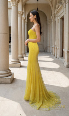 A woman in the Long Formal Dress: Terani 261P6187 stands in an elegant outdoor corridor with columns and arches, her fitted yellow gown radiating sophistication.