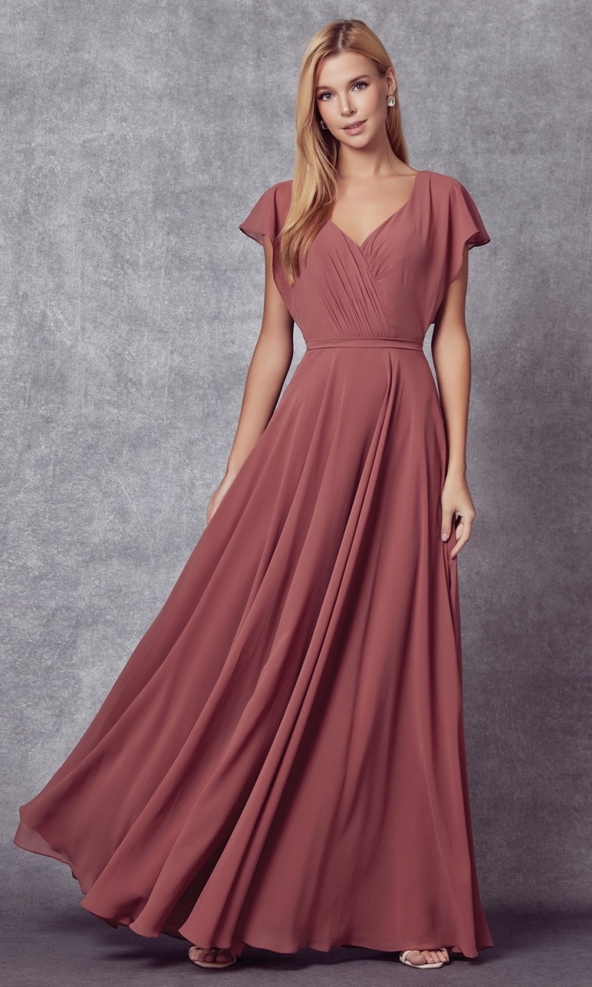 A woman poses against a gray backdrop in the Flutter-Sleeve Long Formal Evening Gown 261—a floor-length, dusty rose A-line dress featuring flutter sleeves and a flattering v-neckline.