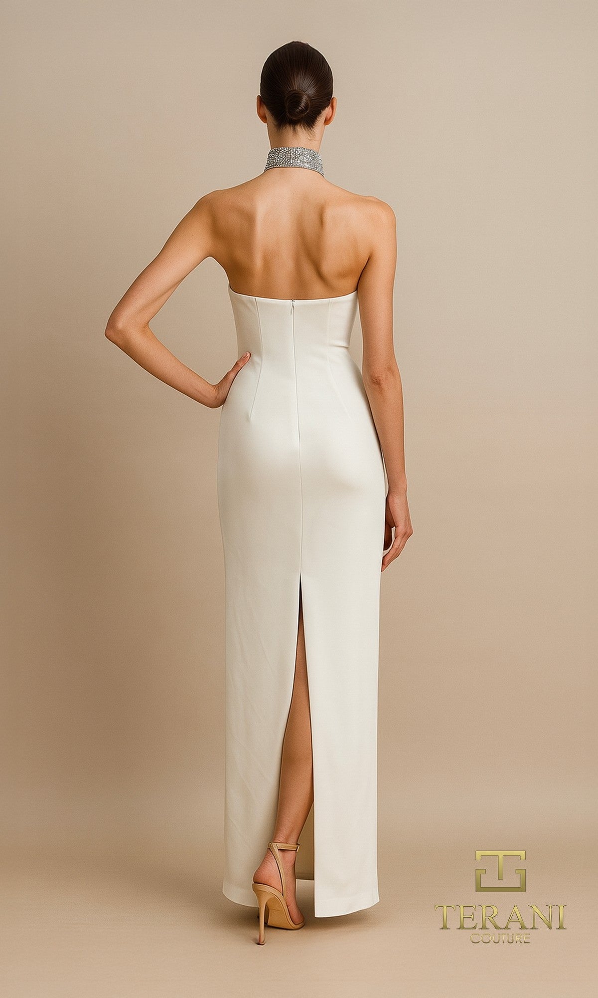 A woman faces away in the Long Formal Dress: Terani 261E6119, a strapless formal gown with a high back slit, accessorized with a silver choker and nude heels. The beige background displays the Terani Couture logo in the corner.
