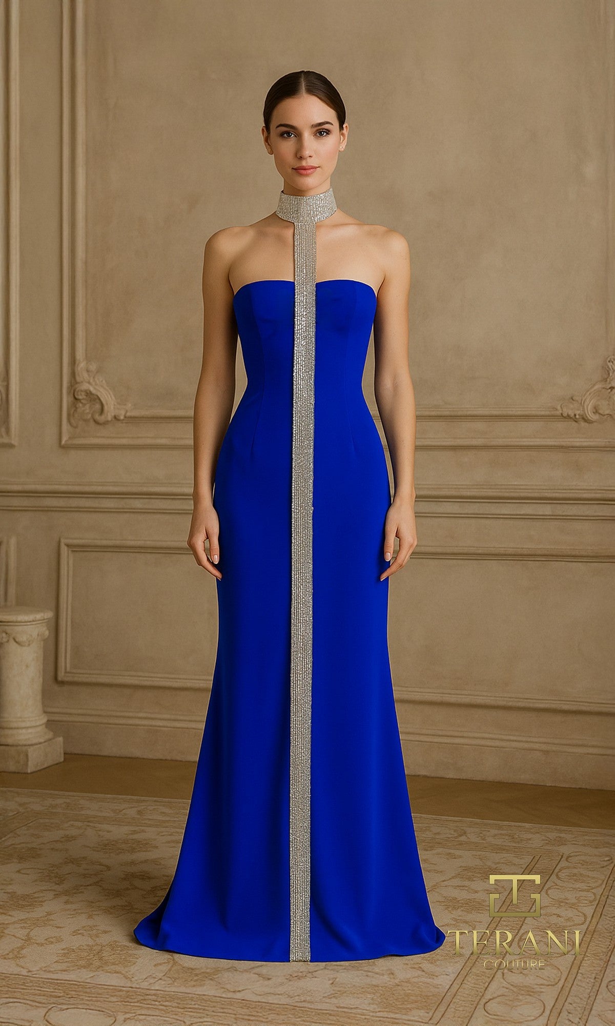 A woman stands in an ornate room wearing the Terani 261E6119 long formal dress in Royal?a floor-length, strapless gown with a vertical crystal-embellished detail and a matching silver neckpiece.
