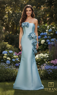 A woman in a fitted, light blue Long Formal Dress: Terani 261E6698 with large 3D floral appliques stands in a garden of blooming hydrangeas. The Terani Couture logo appears in the lower right corner.