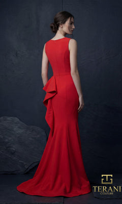 A woman wears the Long Formal Dress: Terani 261E6750?a fitted, floor-length red gown with ruffled back detail and a mermaid silhouette?standing against a dark textured background. "Terani Couture" logo is at the bottom right.