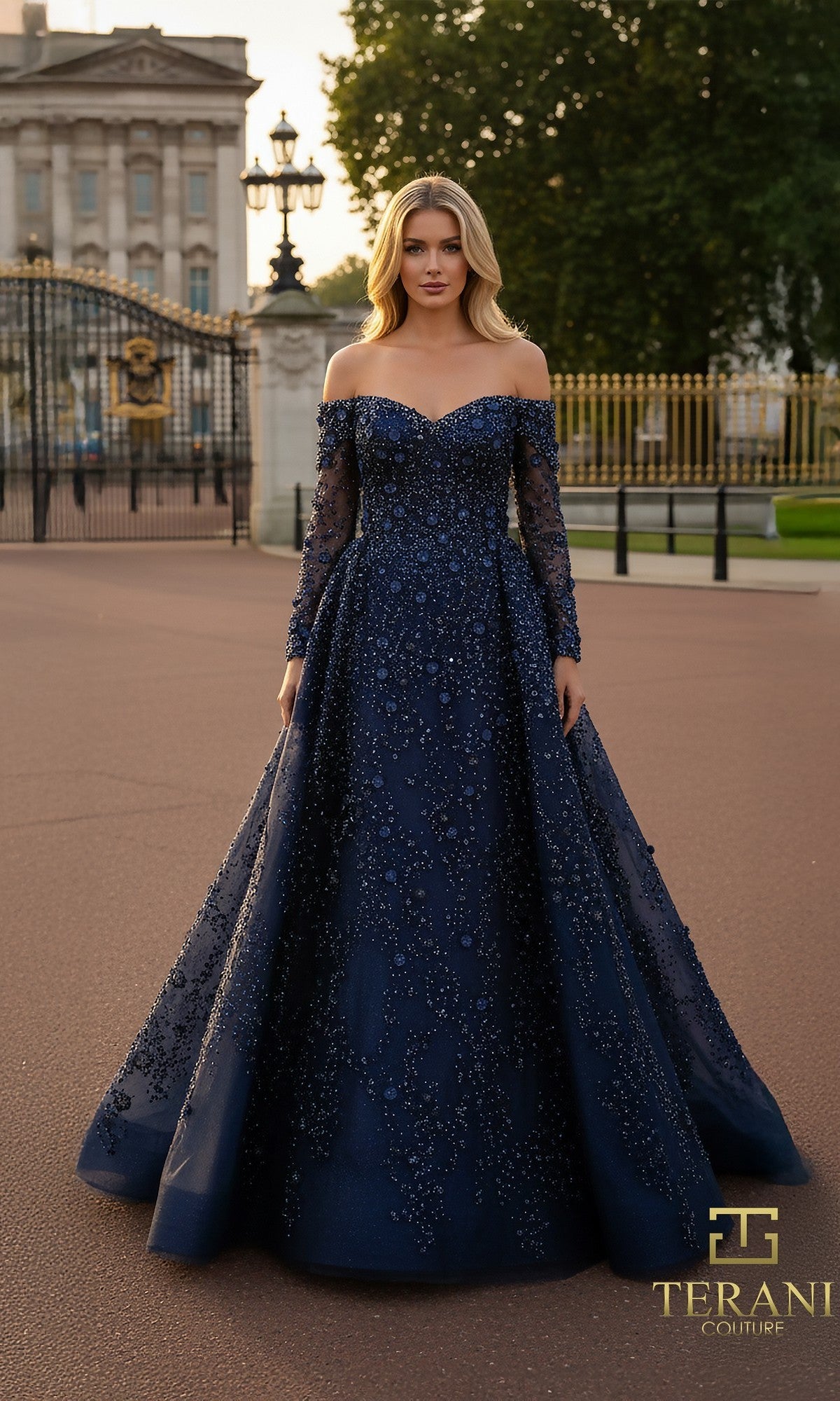 A woman in a navy Terani 261GL6659 long formal dress stands outdoors before ornate gates and a historic building.