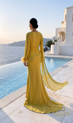 A woman in the Terani 261M6403 long formal dress with sheer sleeves and feathered cuffs stands by a pool with sea views and white buildings in the background.