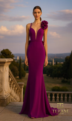 A woman stands outdoors in a violet Long Formal Dress (Terani 261P6061) featuring floor-length stretch fabric and a large flower detail on the shoulder, with trees and a scenic landscape in the background.