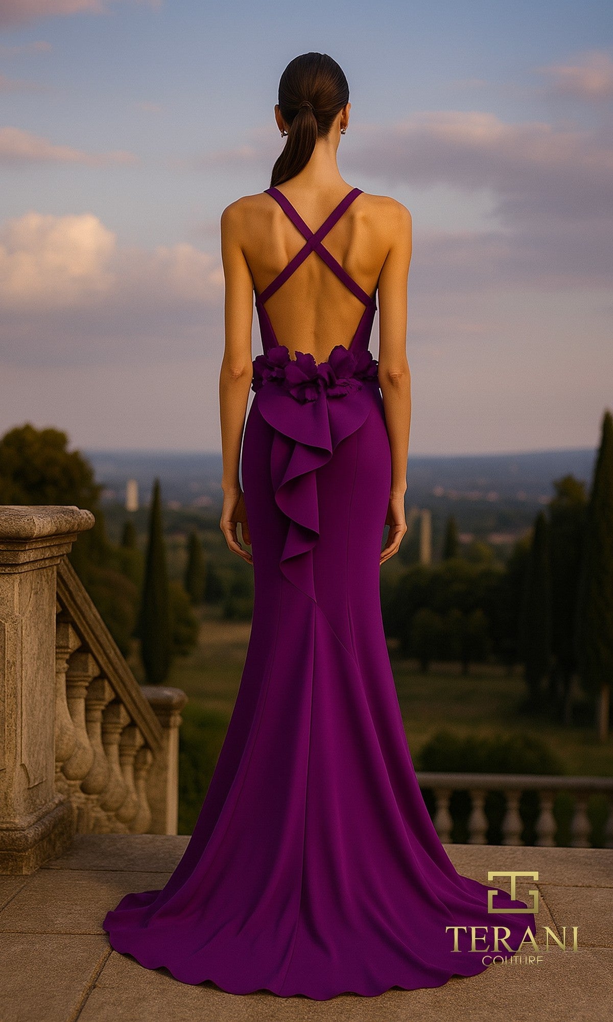 A woman in the Long Formal Dress: Terani 261P6061, a purple gown with crisscross straps and floral details, stands on stone steps overlooking a scenic landscape.