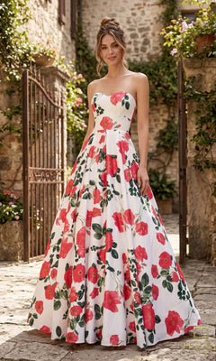 A woman stands outdoors in a cobblestone courtyard wearing the Terani 261P6705 long formal dress in fuchsia multi, featuring a floor-length satin design with a sweetheart neckline and floral print.