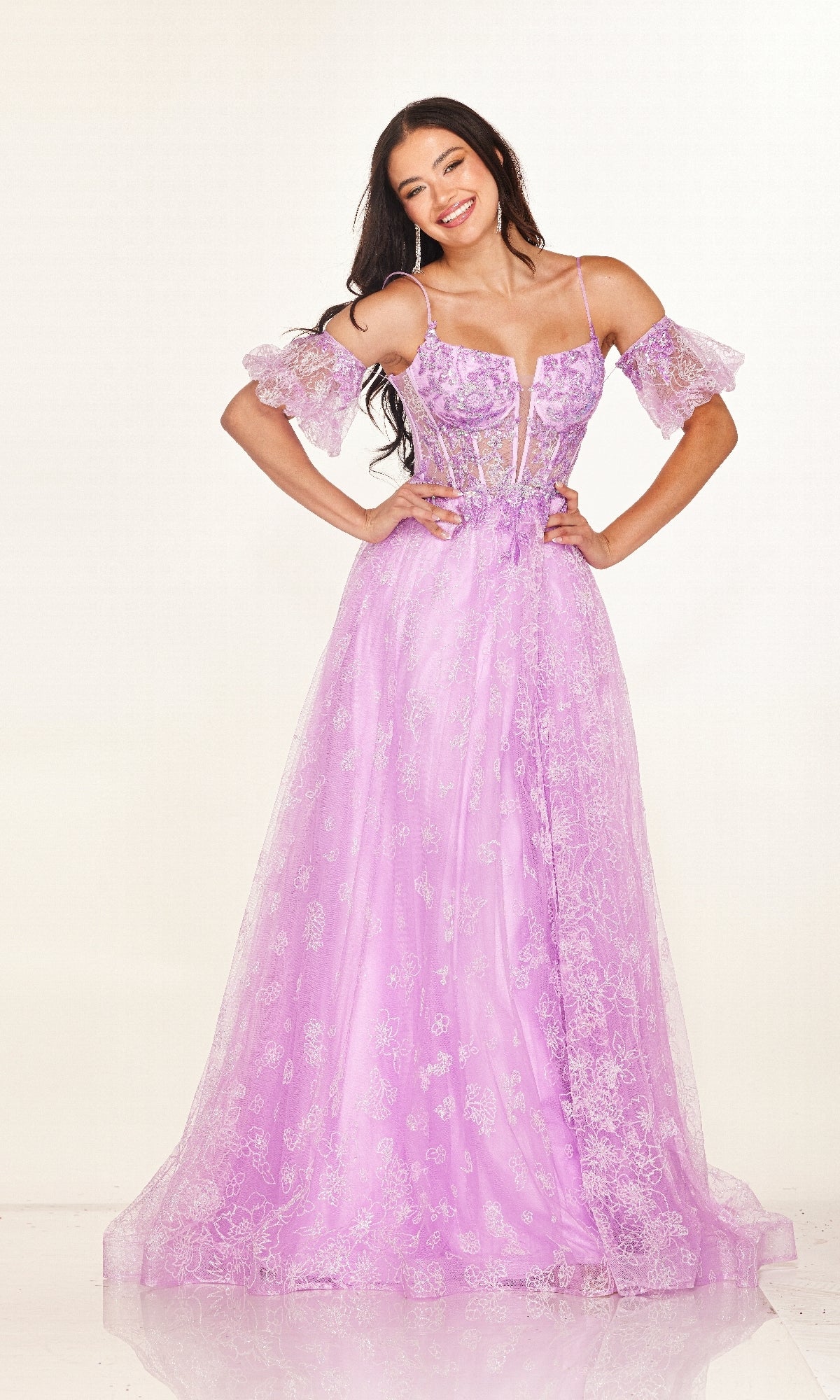 A woman models the Long Prom Dress: Cecilia Couture 2620—a lavender lace gown with off-the-shoulder sleeves and a sheer corset bodice—standing against a plain white background.