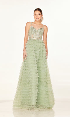 A woman wears the Long Prom Dress: Cecilia Couture 2624—a light green A-line gown featuring a sequined bodice, thin straps, tiered tulle skirt, and lace-up back—while standing against a plain white background.
