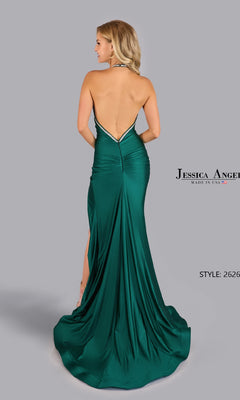 A woman models the Jessica Angel 2626 Open-Back Halter Prom Gown in emerald green, featuring a backless design and long train, posing with her back to the camera against a plain gray background.
