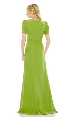A woman faces away, wearing the Mac Duggal 2630 short-sleeve long formal dress in light green, featuring a fitted bodice and a flowing floor-length skirt.