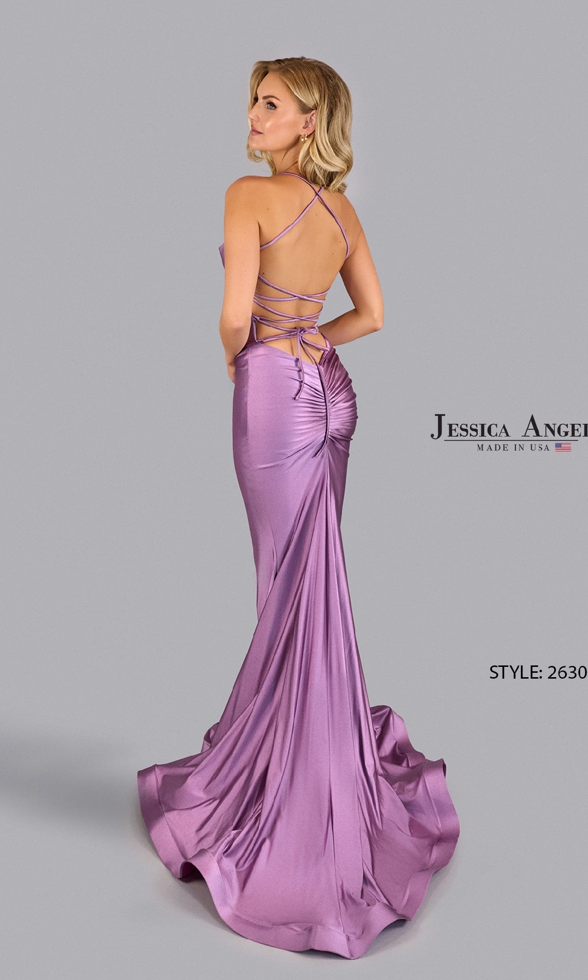 Woman in a lavender, floor-length satin Jessica Angel 2630 cowl-neck prom dress with a ruched and strappy open back, posed against a plain gray background. Text on image: 