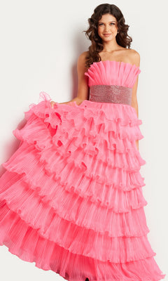 A woman stands against a plain white background wearing the Jovani Strapless Long Tiered Prom Ball Gown 26314 in bright pink, featuring multiple ruffled tiers and a beaded waistband.