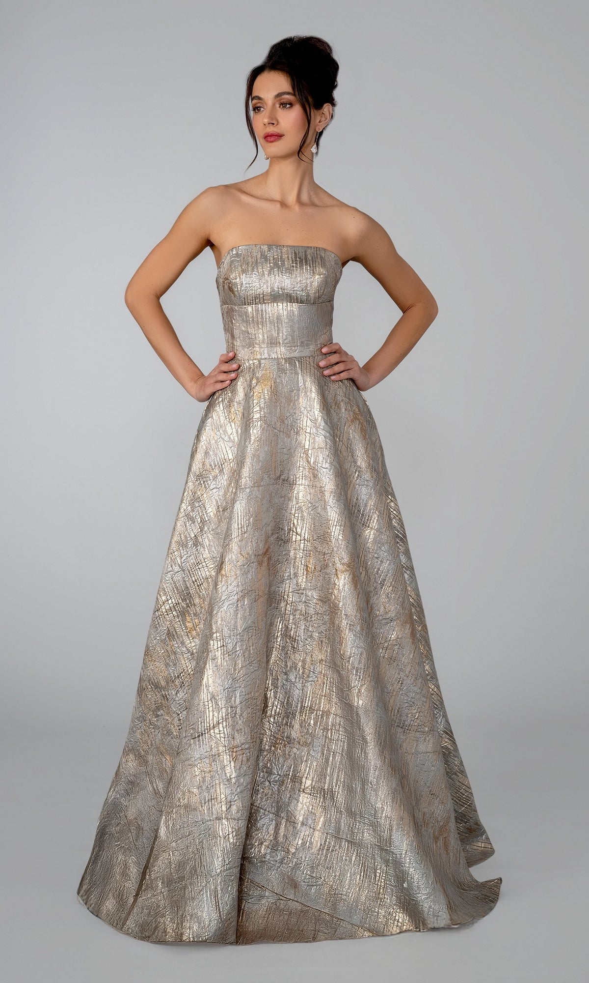 The Stella Couture 26316 is a gold strapless A-line evening gown in a floor-length silhouette with a textured metallic finish.