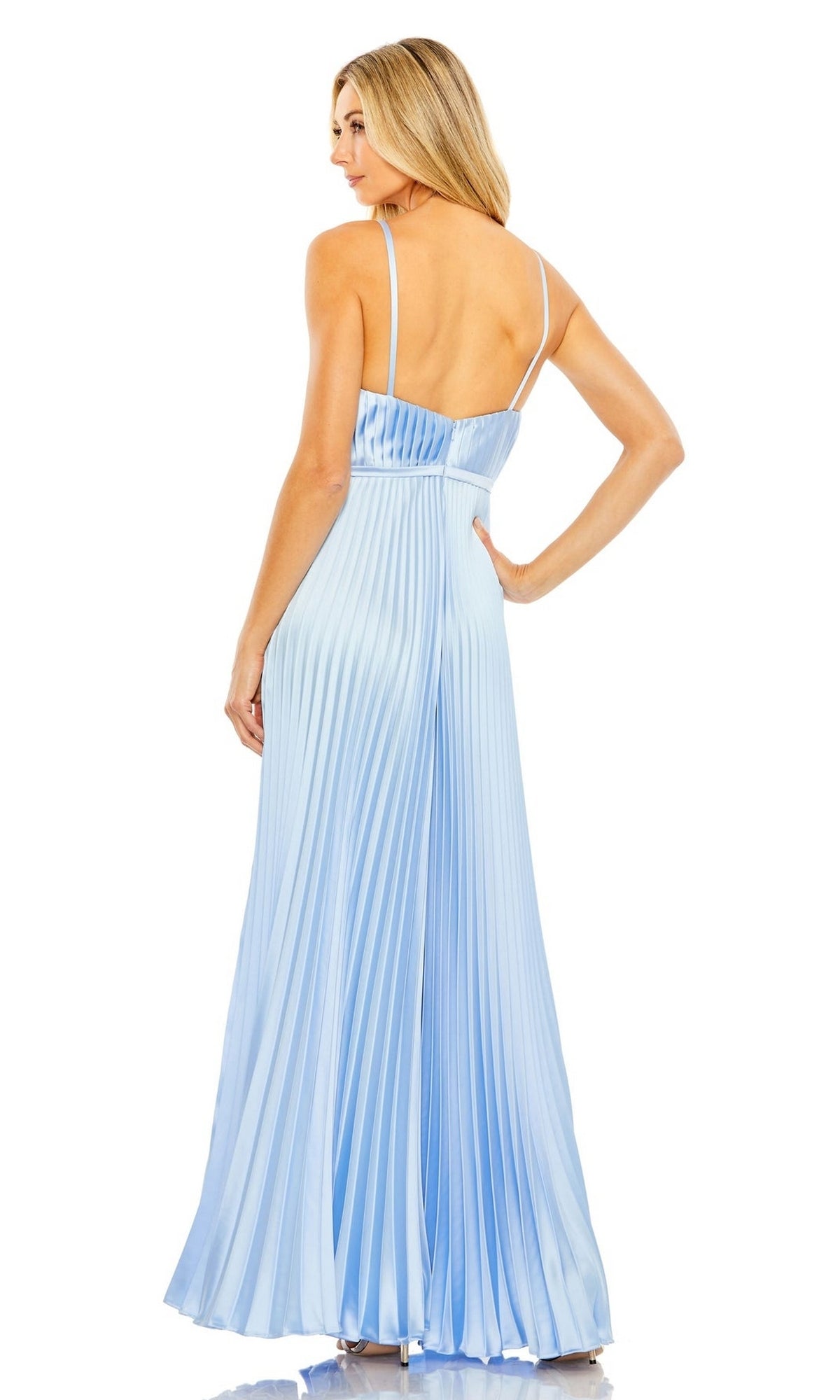 A woman in the Mac Duggal Pleated Wide-Leg Formal Jumpsuit 26319, a long light blue pleated piece with thin straps, stands facing away and looks over her shoulder against a white background.