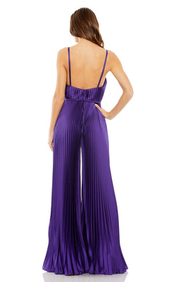 A woman stands with her back to the camera, wearing the Mac Duggal Pleated Wide-Leg Formal Jumpsuit 26319—a sleeveless, floor-length purple jumpsuit with thin straps and a pleated wide-leg design.