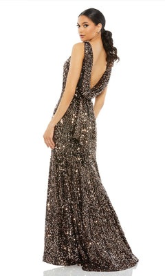 A woman stands looking over her shoulder in the Mac Duggal 26331 Cowl-Back Long Sequin Prom Dress, a floor-length, sleeveless black and gold gown with sparkling sequins.