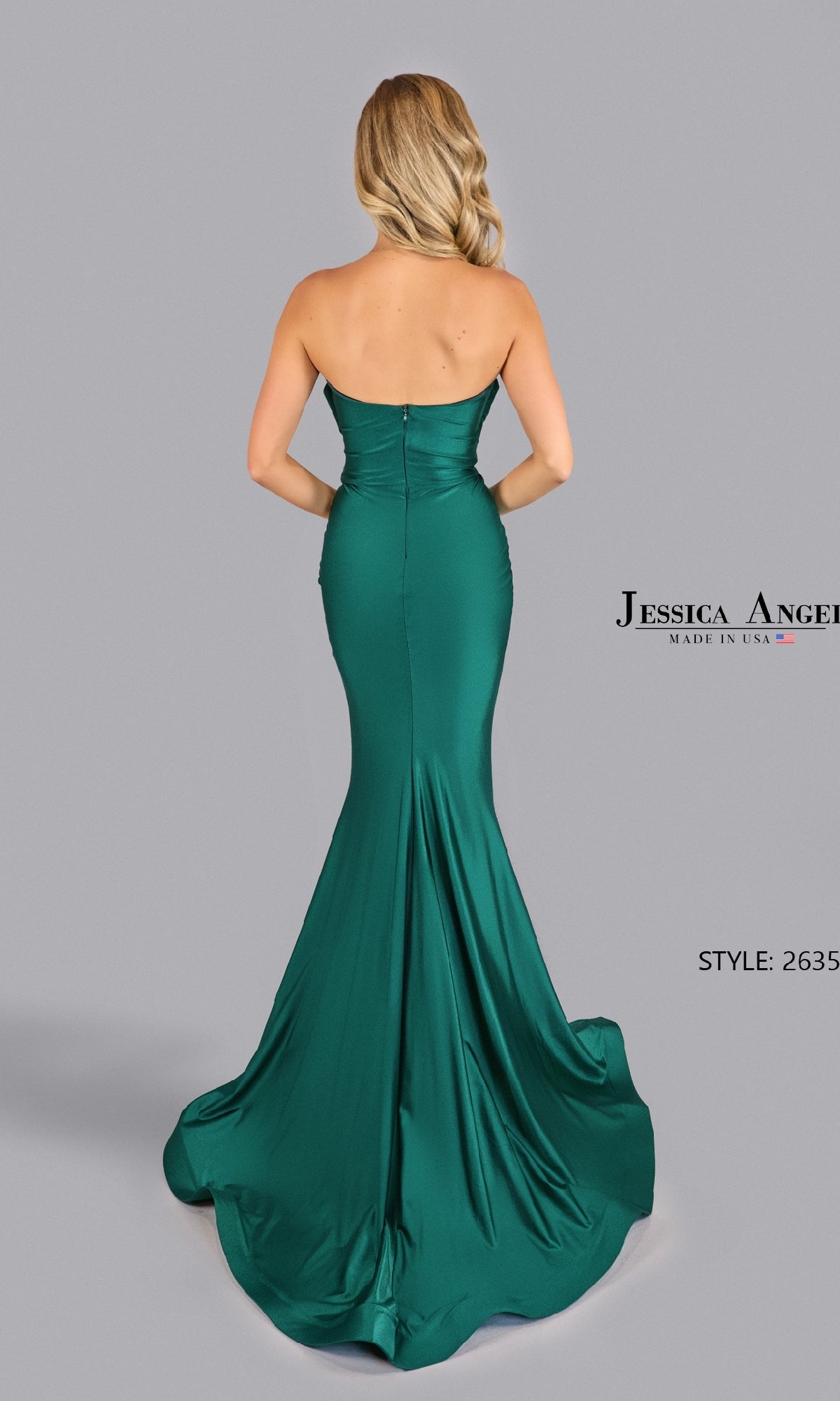 Woman in the Pleated Strapless Prom Gown: Jessica Angel 2635 stands facing away, highlighting the elegant, floor-length emerald green mermaid dress against a plain gray background.