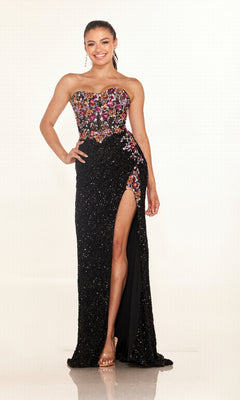 A woman poses and smiles against a plain light background wearing the Cecilia Couture 2635—a strapless black sequin long prom dress featuring a floral embroidered sheer corset bodice and a high leg slit.