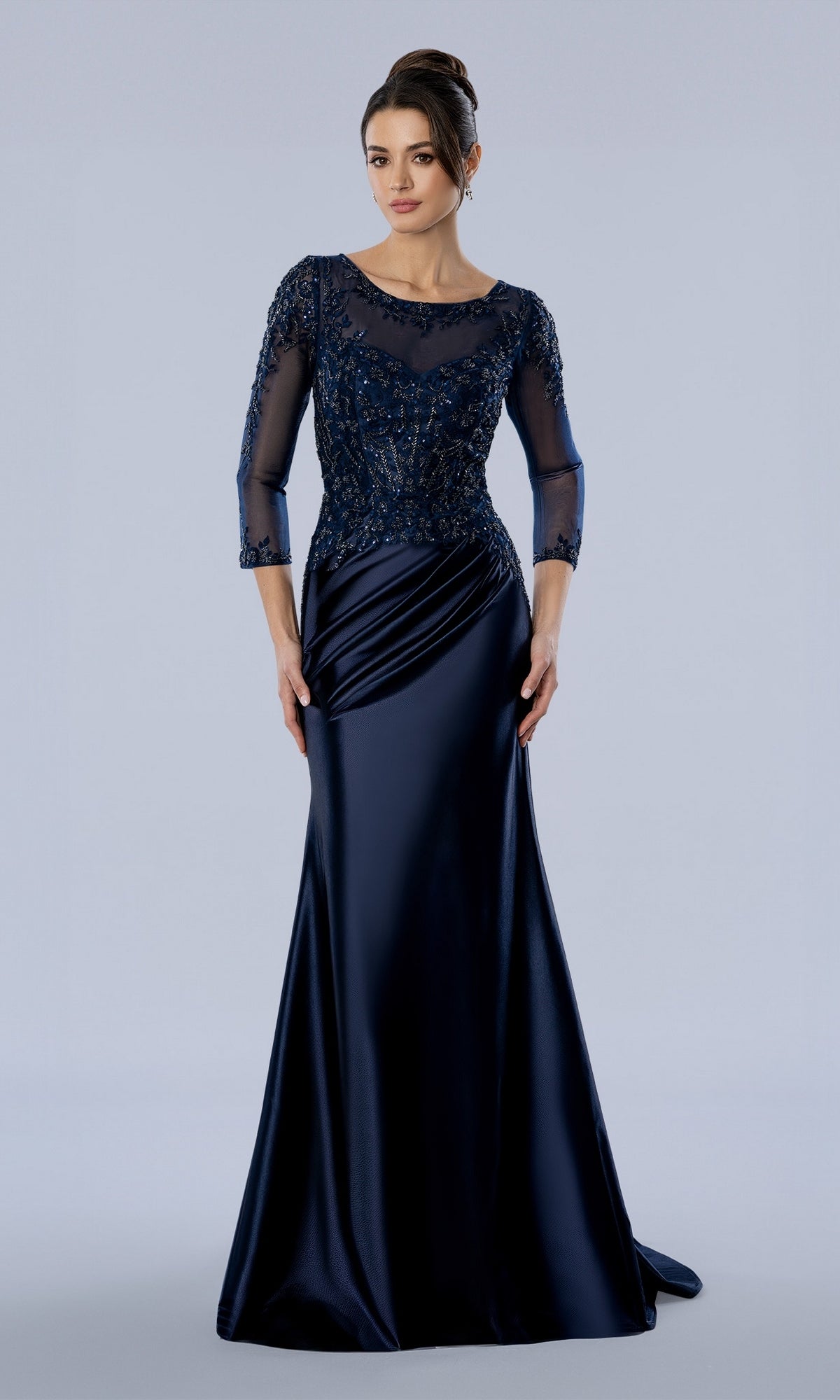 The Stella Couture 26380 is a navy blue mother of the bride evening gown with a floor-length silhouette, sheer beaded bodice, and three-quarter length sleeves.