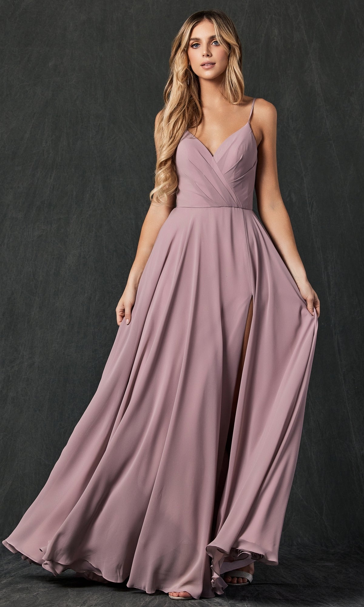 A woman wears the Simple Long Formal Dress with Lace-Up Back 263, a sleeveless, mauve evening gown with a V-neckline, fitted bodice, and high slit, standing against a dark background.