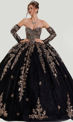 A woman in the Quinceanera Dress 26402 by Stella Couture, a stunning black strapless ball gown adorned with gold floral embellishments, featuring a beaded corset bodice and a glitter tulle skirt, accessorized with matching gloves and a necklace, poses gracefully with her hands on her waist.