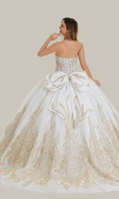 A woman wearing the Quinceanera Dress 26405 by Stella Couture, a strapless white ball gown with a corset bodice, gold embellishments, and a large back bow, stands against a plain beige background.