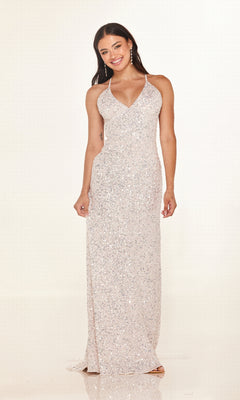 A woman stands and smiles against a plain light background, wearing the Cecilia Couture 2640 long prom dress—a sleeveless, floor-length silver sequin gown with a V-neckline.