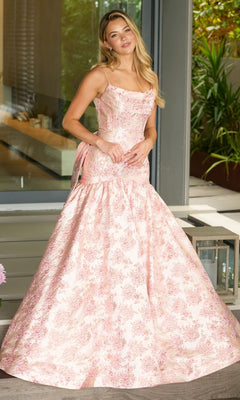 A woman stands outside in front of glass doors, wearing the Ava Presley 26419 Drop-Waist Long Print Prom Gown with a fitted bodice and flared skirt.
