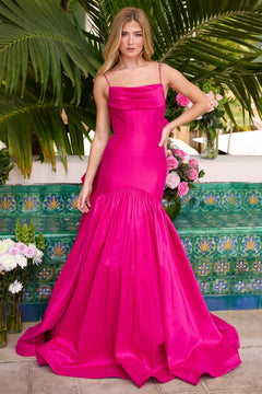 A woman in the Ava Presley 26422 Drop-Waist Mermaid Prom Gown in magenta stands before lush tropical plants and a vibrant tiled wall, surrounded by assorted flowers.