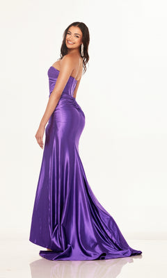 A woman smiles sideways in the Cut-Out Strapless Prom Gown: Cecilia Couture 2643, featuring a corset-style bodice and shiny purple, floor-length skirt, posing against a plain white background.
