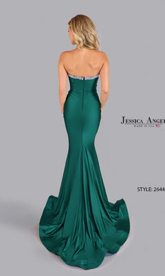 A woman stands facing away from the camera in the Jessica Angel 2644 Cut-Out Strapless Prom Gown—an emerald green, floor-length dress with a fitted silhouette and slight train.