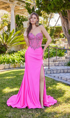 A woman stands outdoors in the Juliet JT2648K long prom dress, featuring a strapless embellished corset bodice and a high leg slit, surrounded by lush greenery and stone pathways.