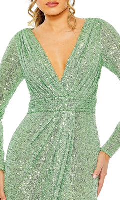 A woman wearing the Mac Duggal 26490 long-sleeve formal dress in sparkly light green, featuring a deep V-neckline and gathered waist detail.